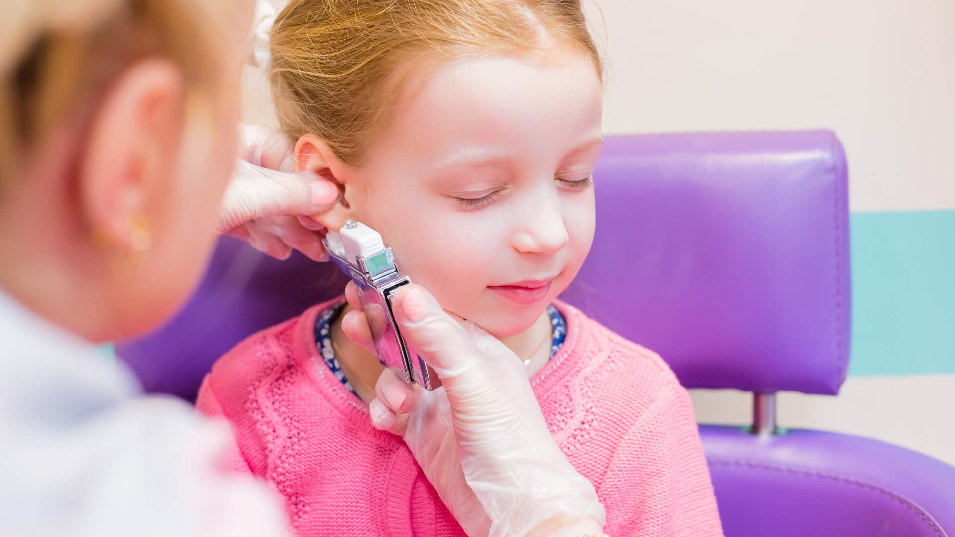 little girl getting her ears pierced using a piercing gun