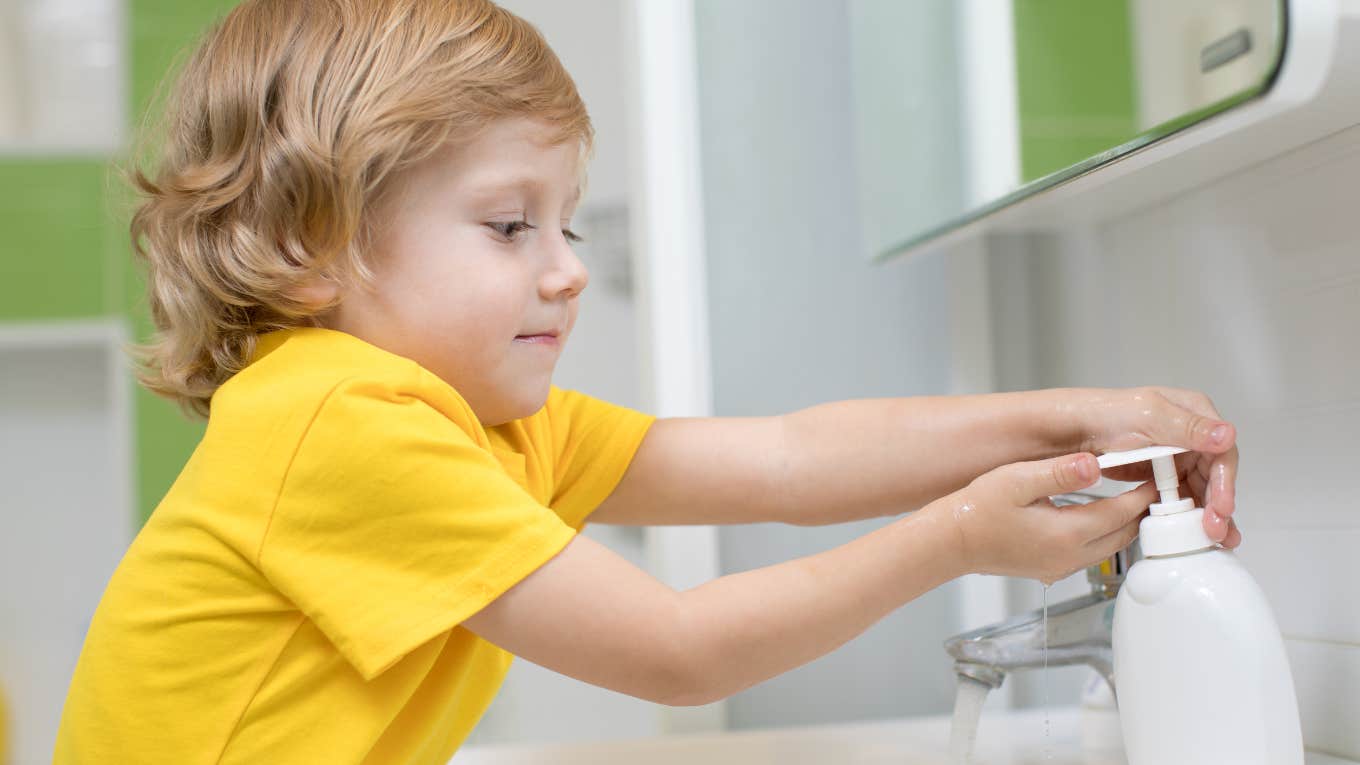 Little boy using soap dispenser to wash his hands in sink