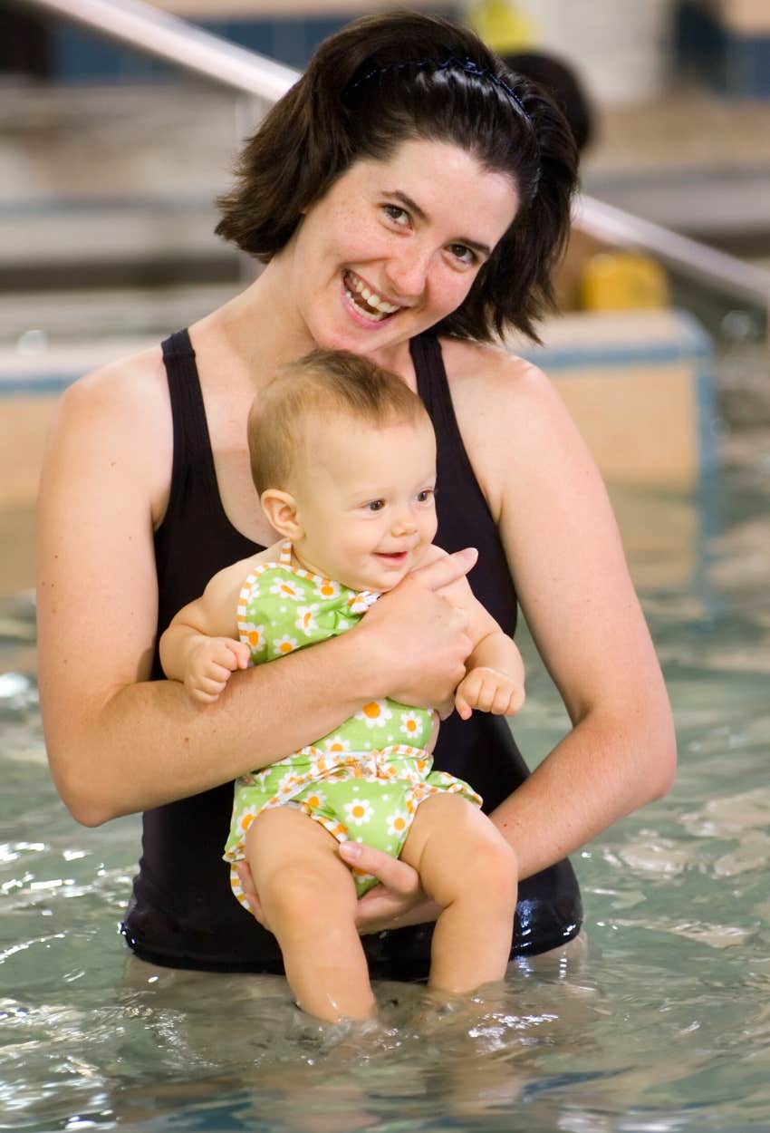 mom holding baby in pool