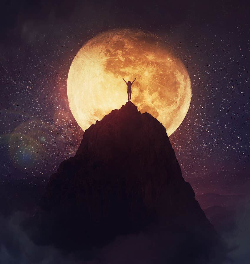 Woman on a mountain top raise arms to the sky and moon