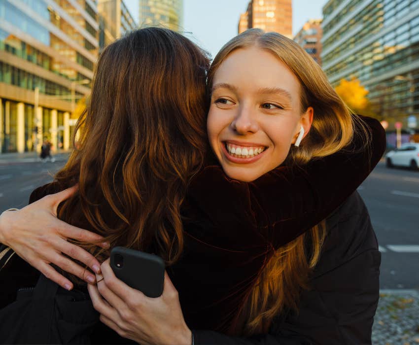 two women hugging with big smile in the city