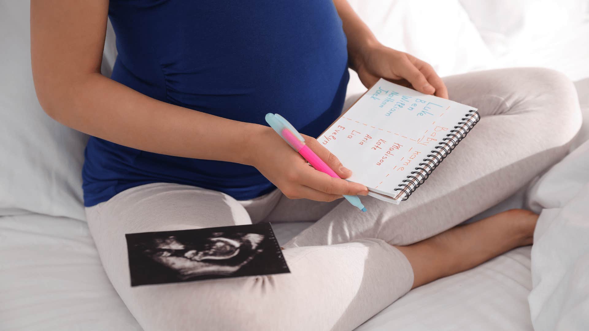 Pregnant person with sonogram image and notebook