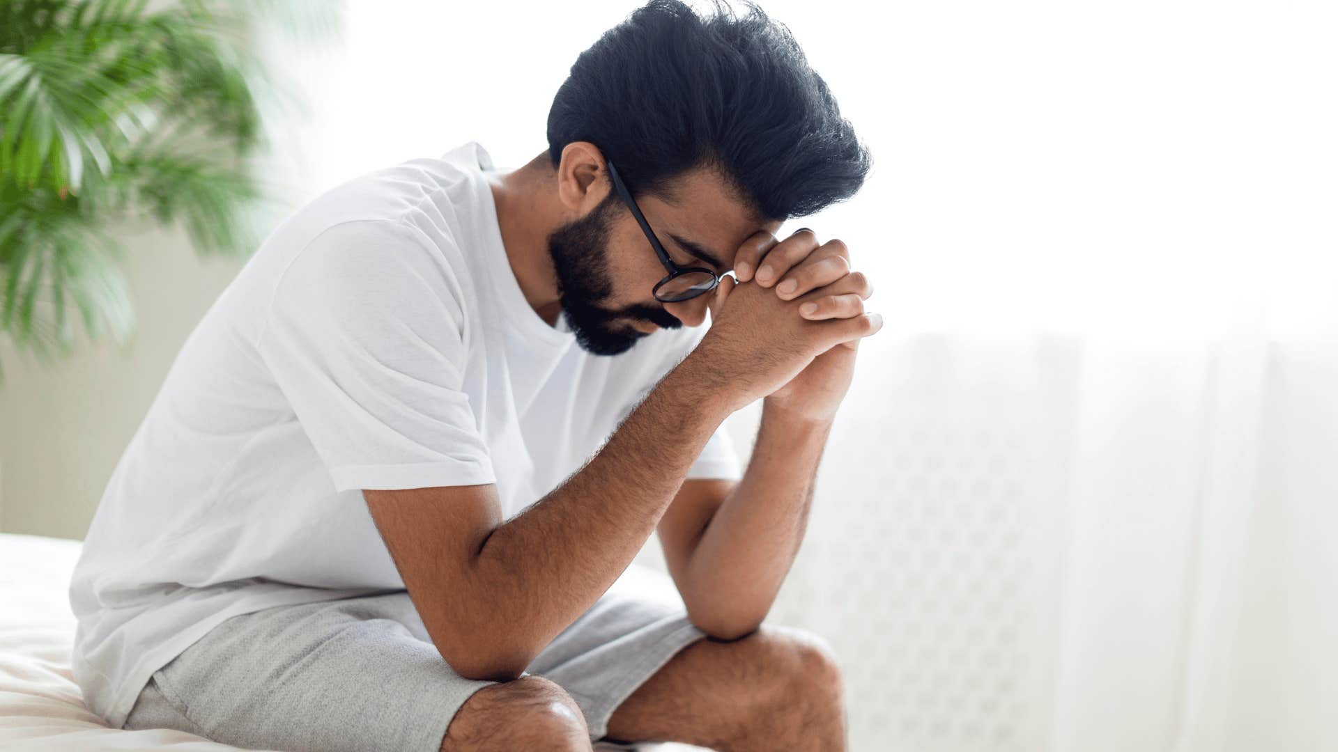 man upset sitting on edge of bed