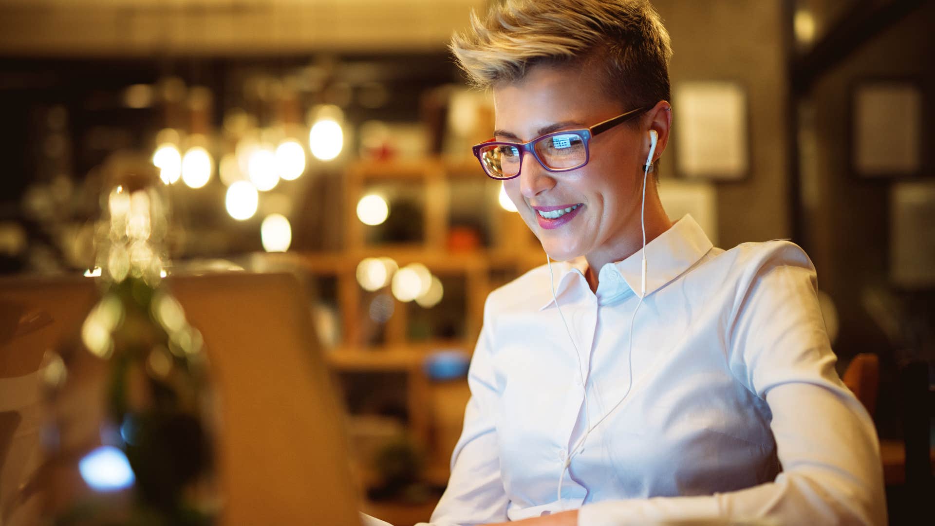 Woman smiling and working on her laptop late at night.