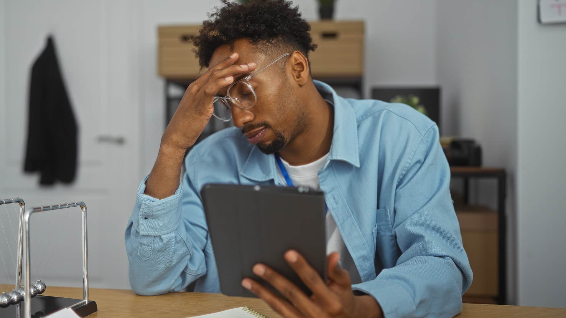 Man looking annoyed staring at his tablet.