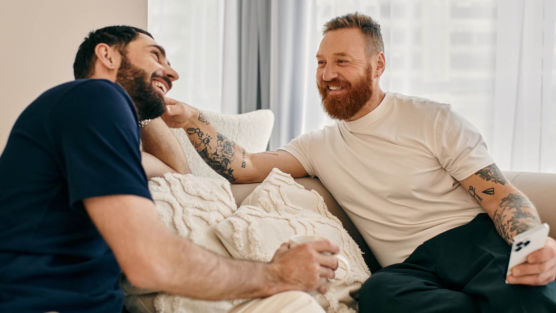 Couple smiling and having a conversation on a couch.