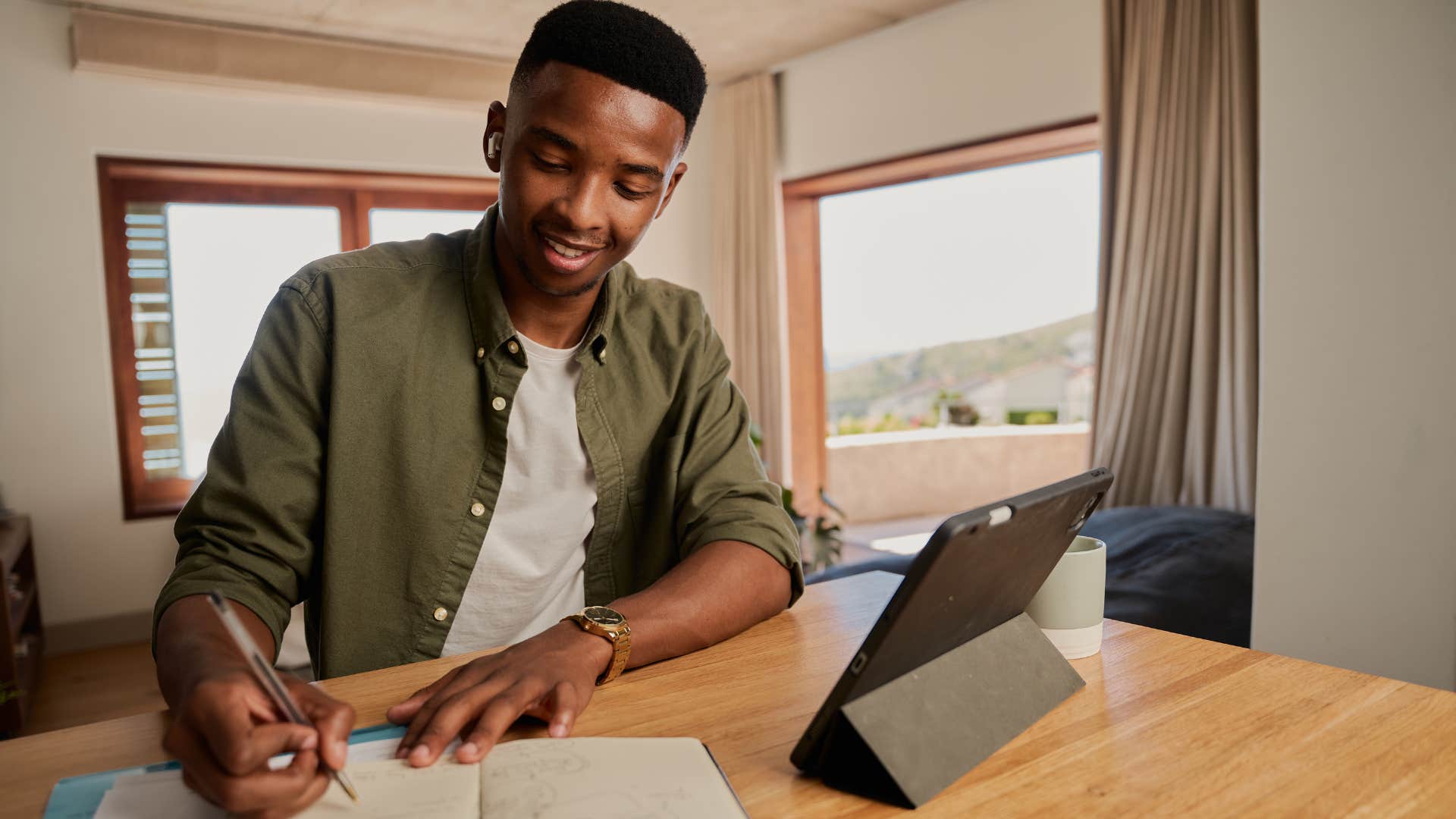 Young man smiling and writing in his notebook.