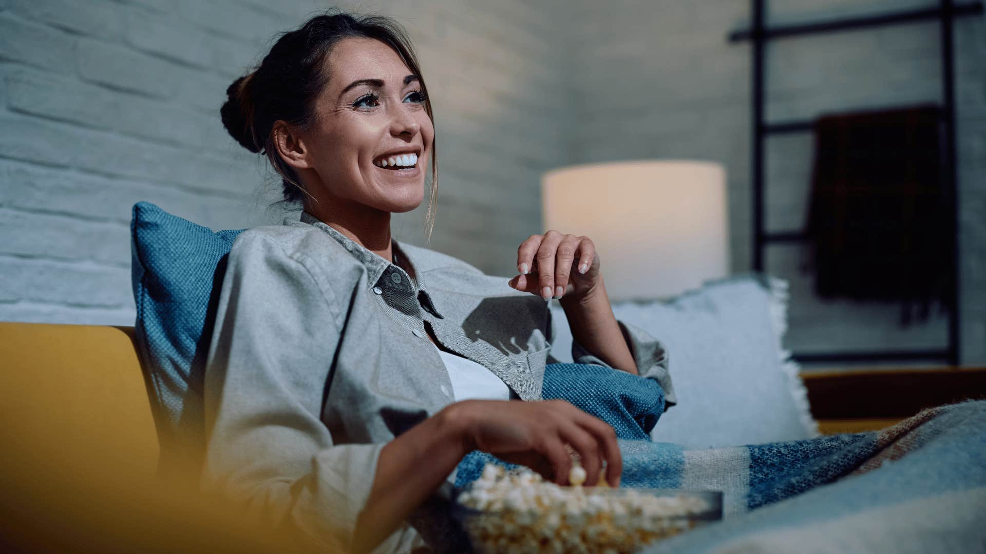 woman watching TV and eating popcorn