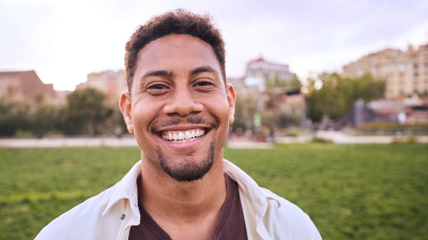 Portrait of cheerful young man standing outdoors and smiling at camera. 