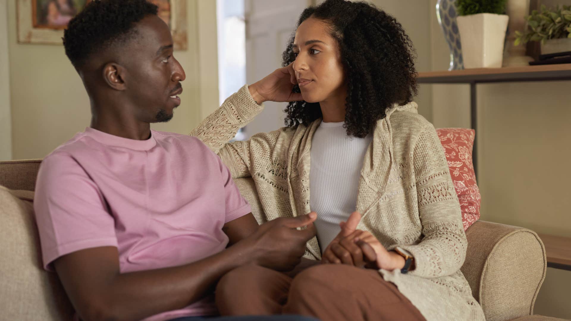 Couple having a serious conversation sitting on a couch together.