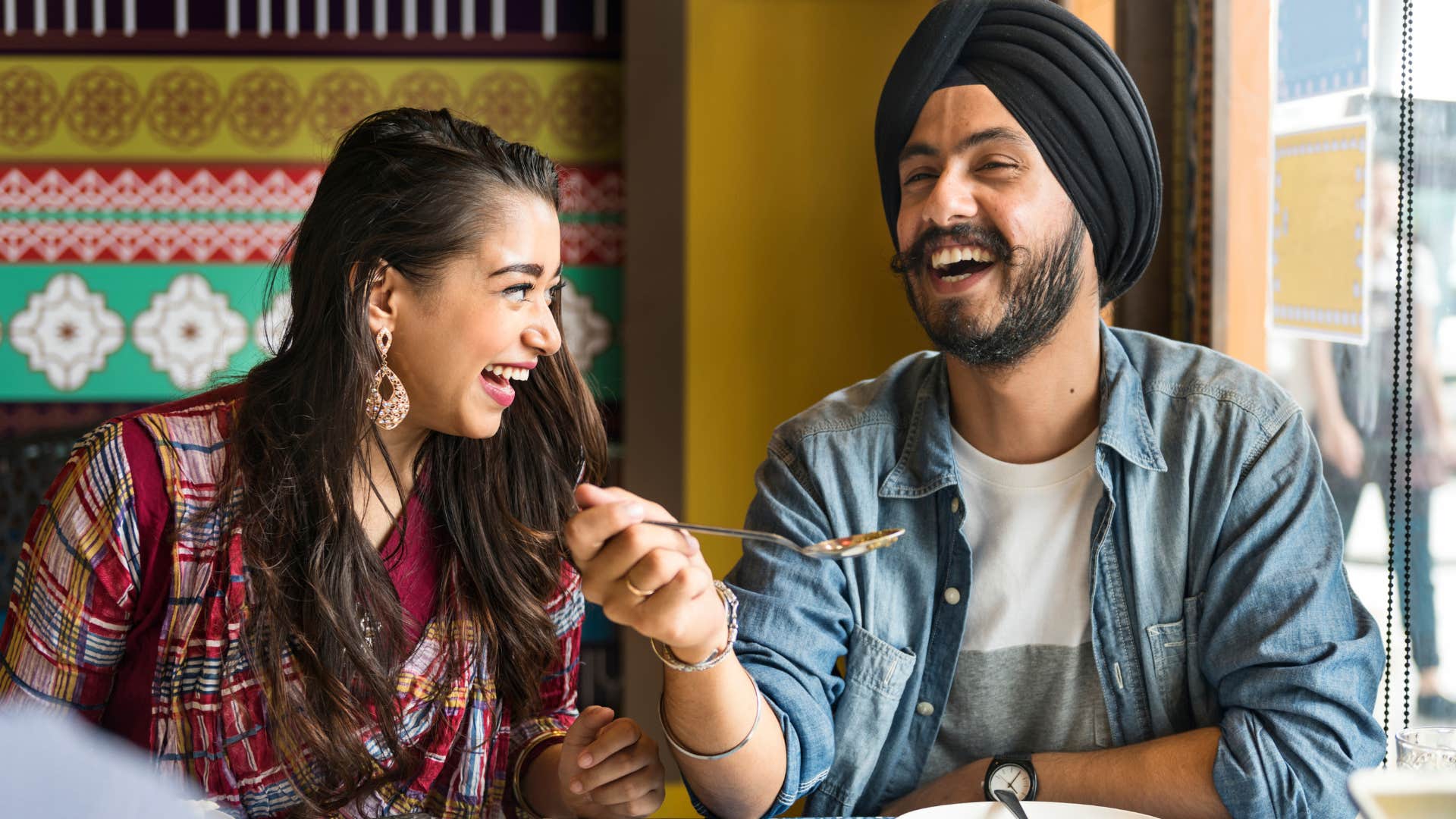 Couple smiling and eating dinner together.