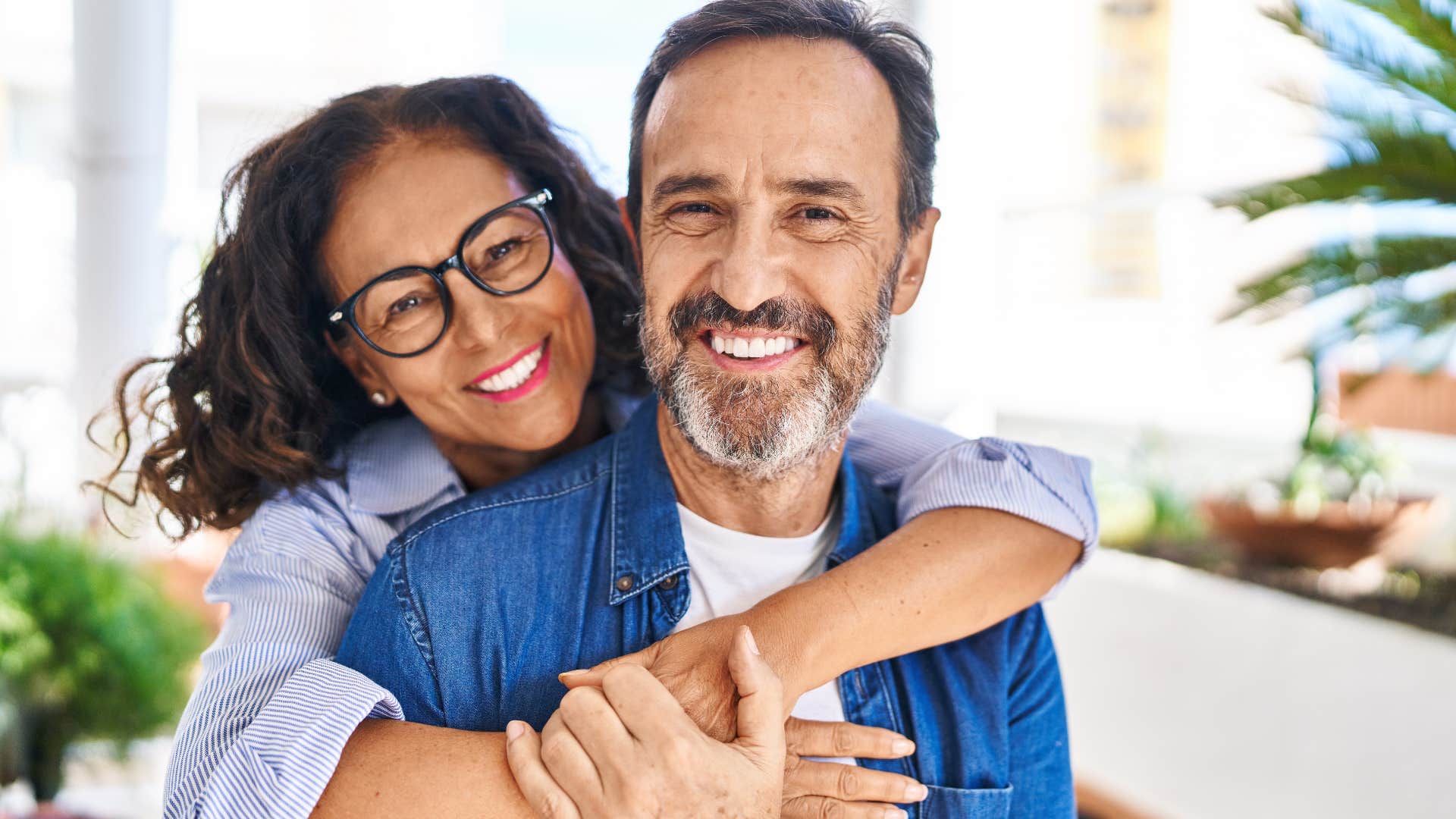 Woman hugging her husband and smiling at the camera.