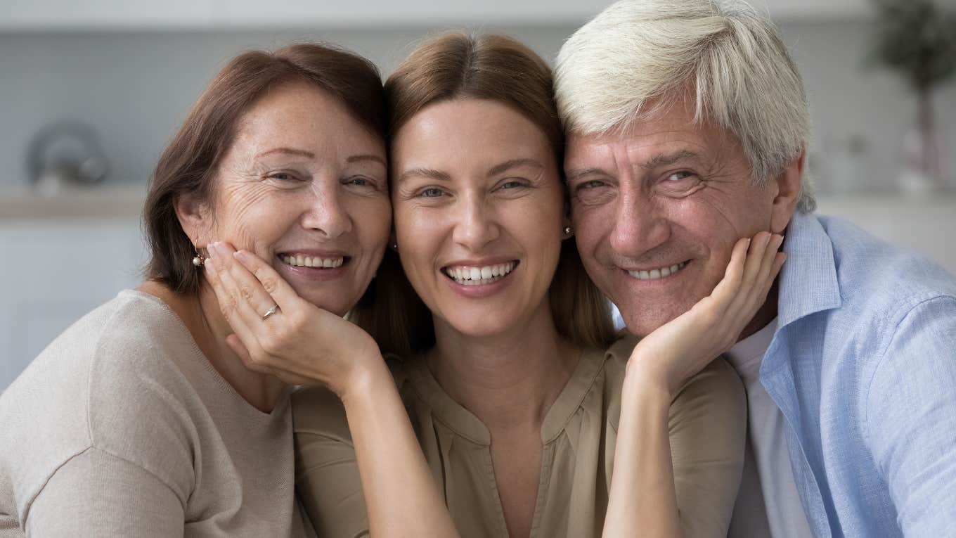 happy older parents with young adult daughter smiling