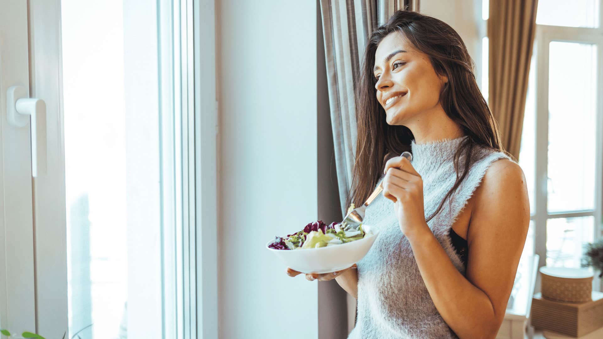 woman eating healthy food looking outside window