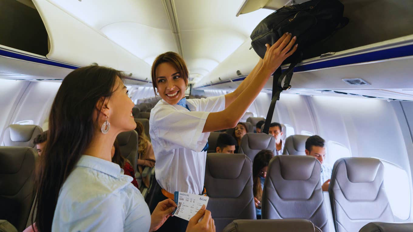 flight attendant putting bag in overhead bin