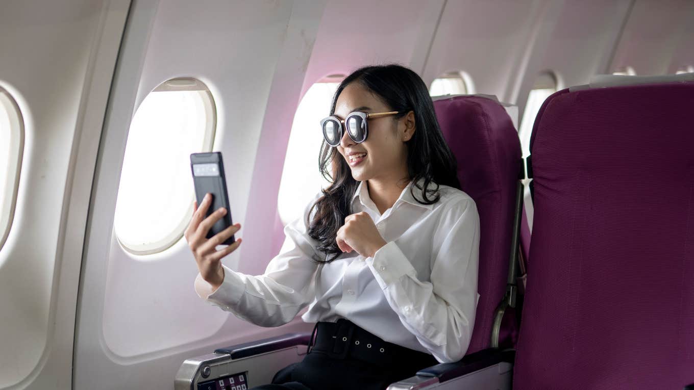 Woman taking a video of herself while flying on a plane