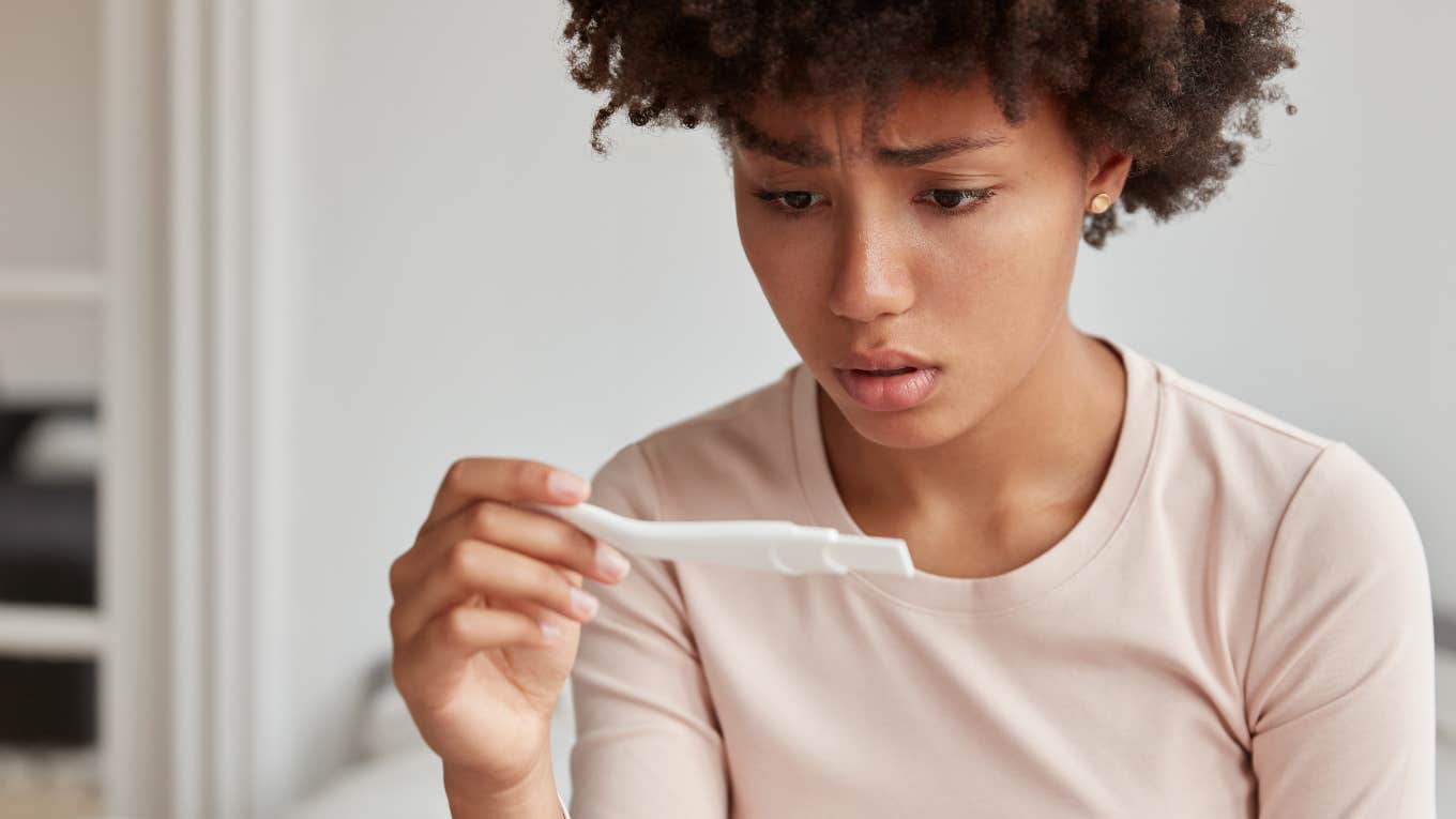 Concerned mom-to-be looking at positive pregnancy test