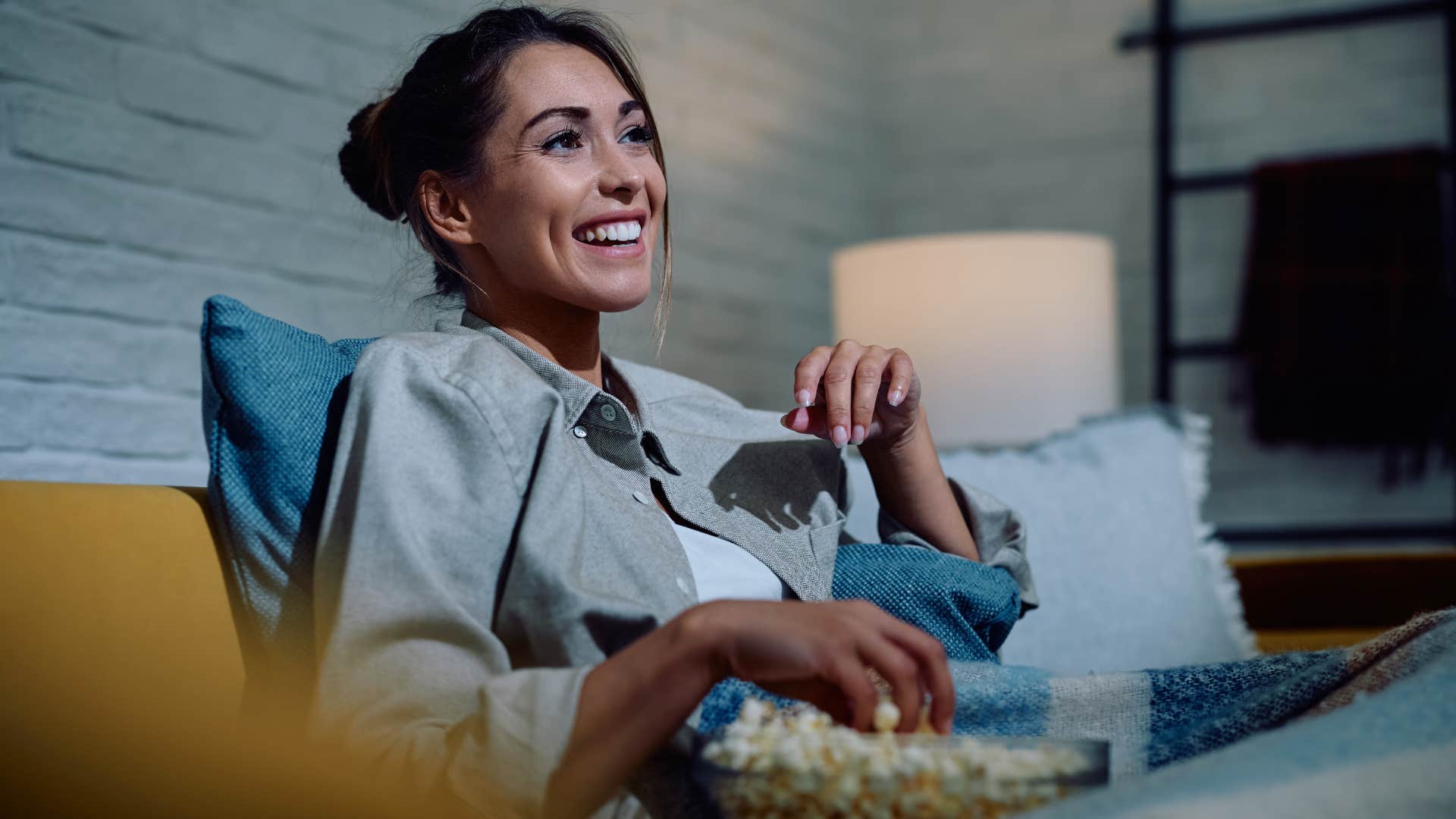 Woman smiling and eating popcorn. 