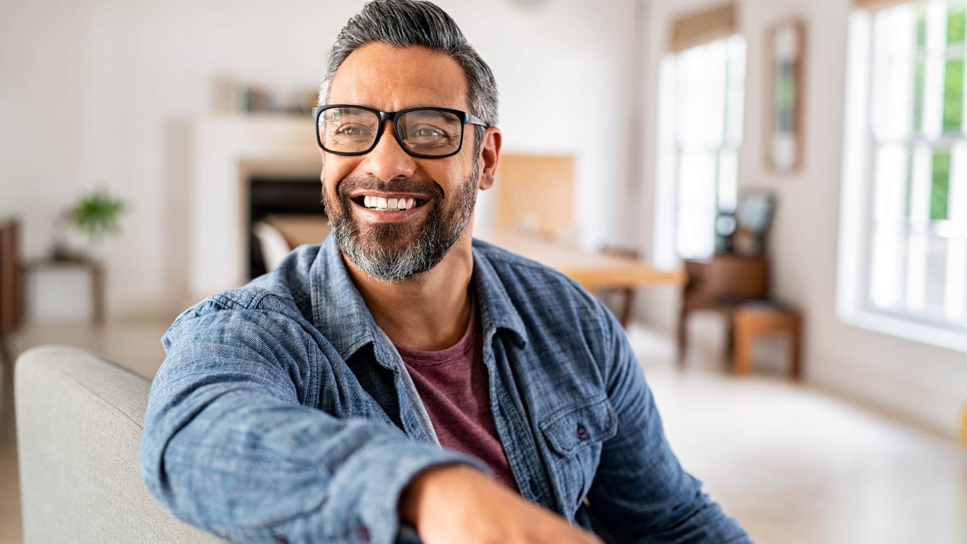 Man smiling while sitting on the couch.