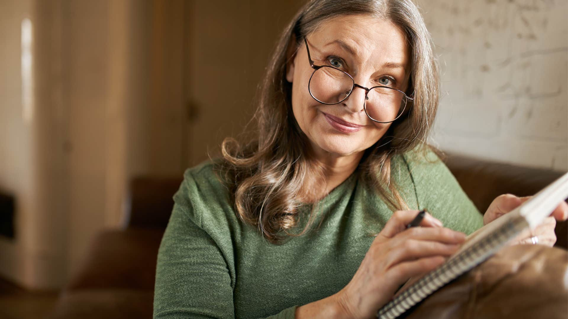 Woman smiling and writing in her notebook.