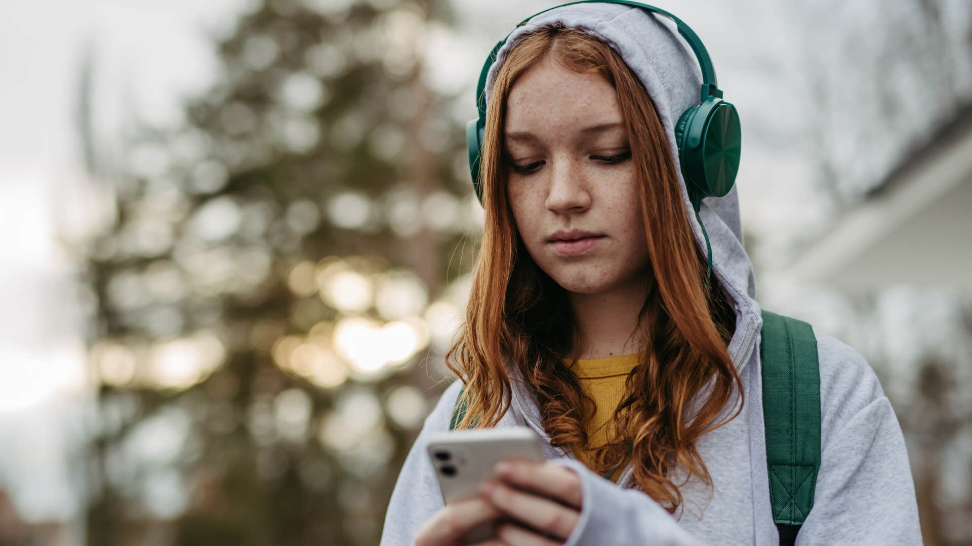 Young woman wearing headphones looking sad.