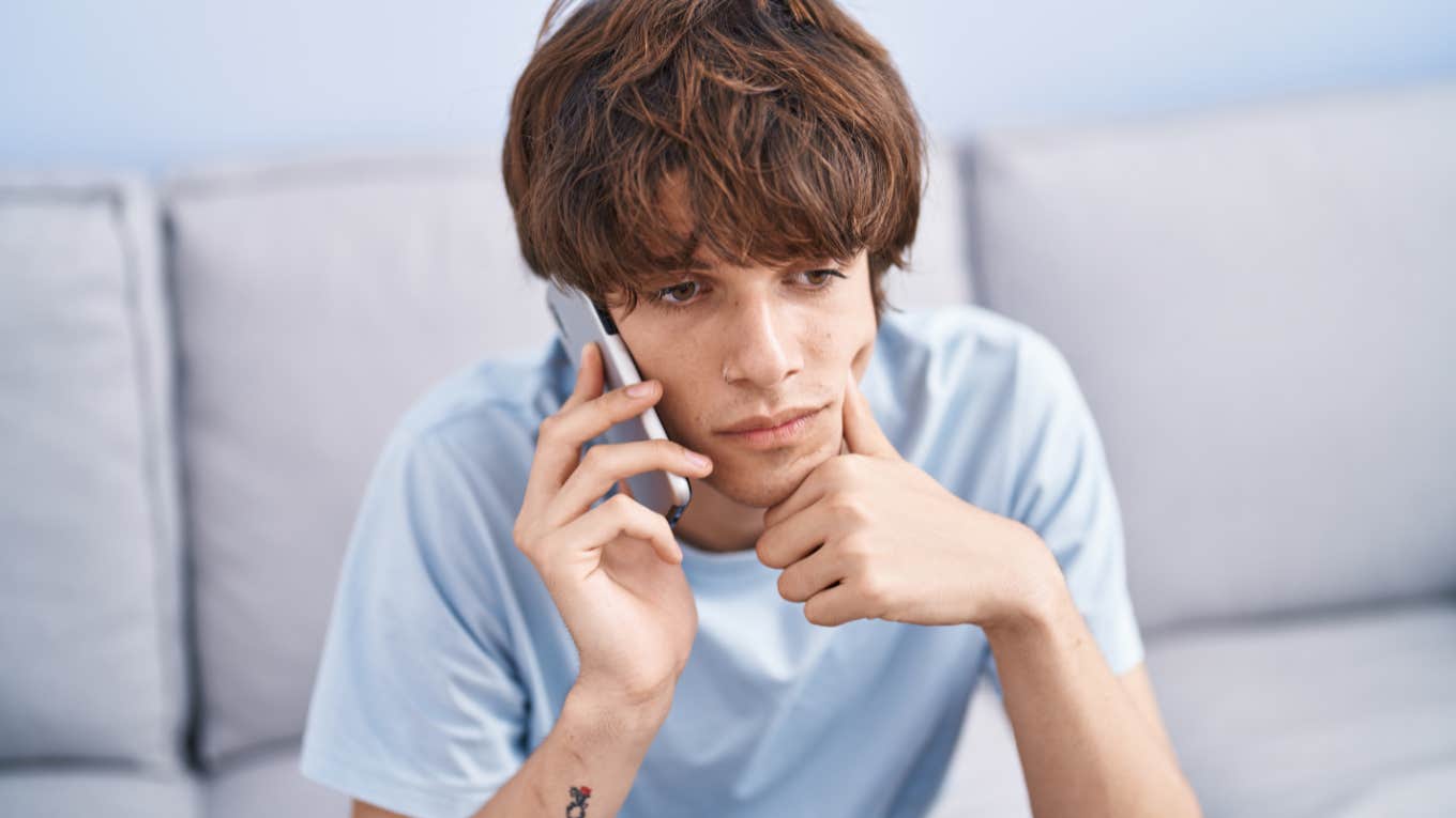 Young man looking bored while talking on the phone.