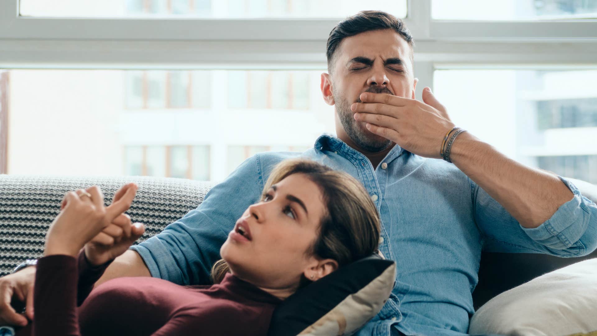 Man yawning while his wife lays on his lap