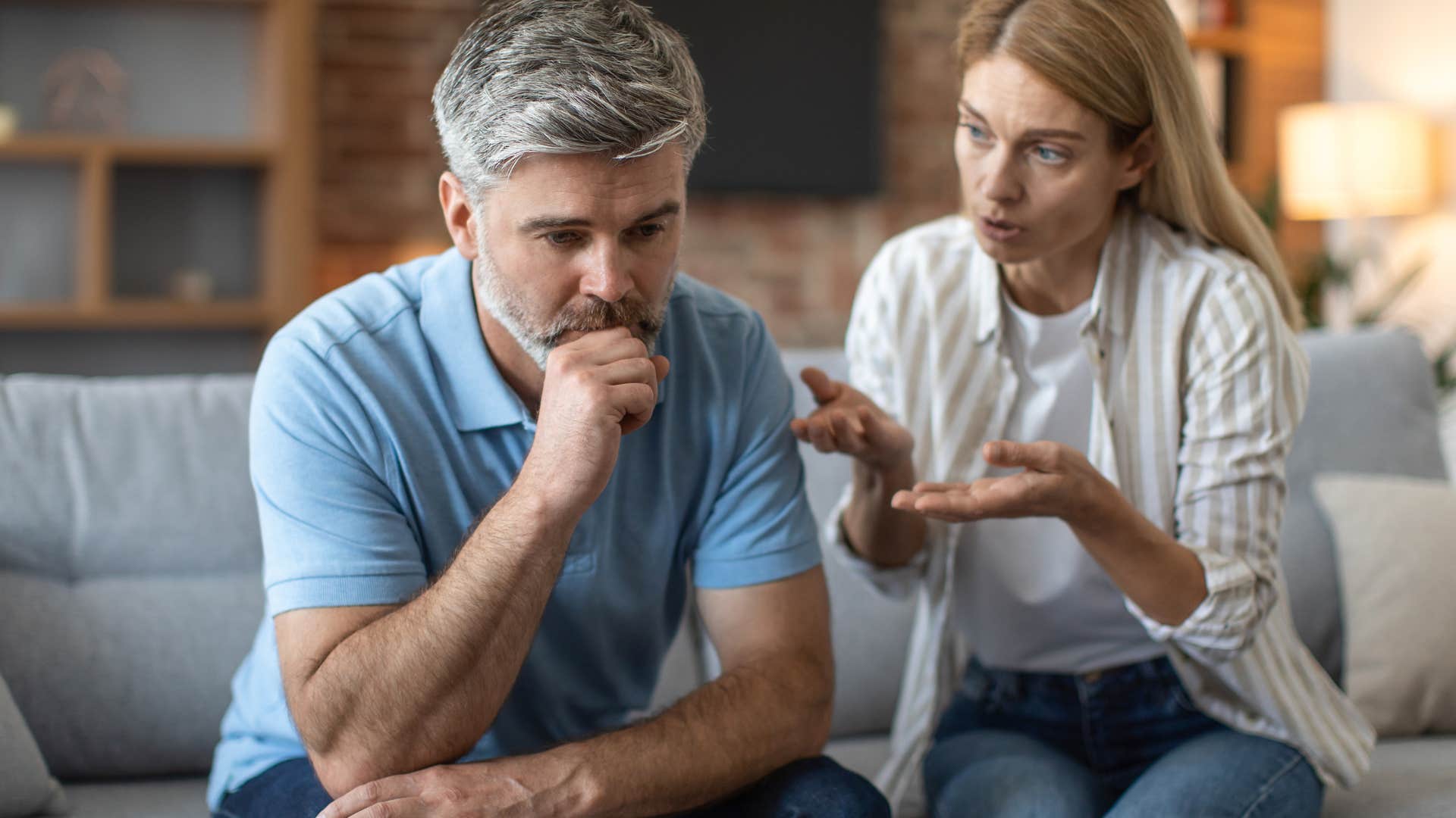 Older man looking upset while his wife argues with him