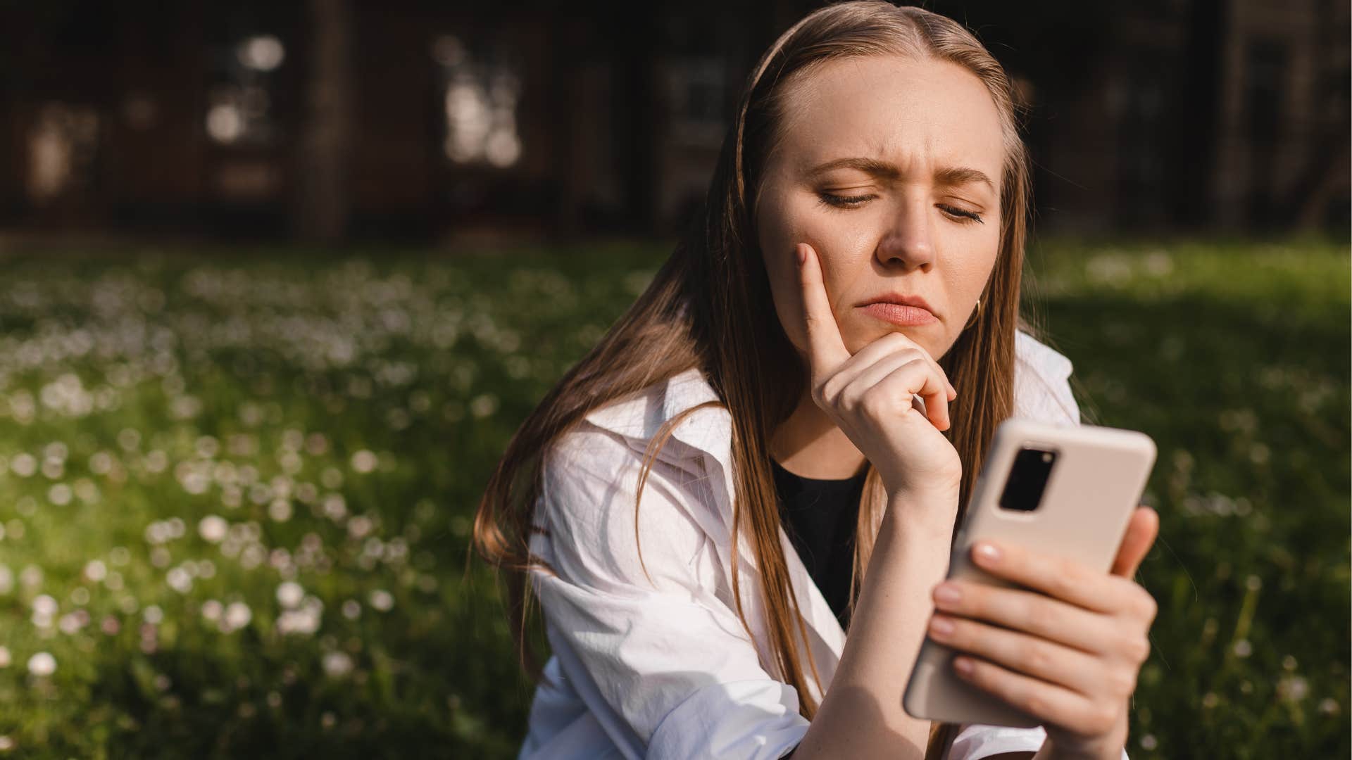 Annoyed woman staring at her phone outside