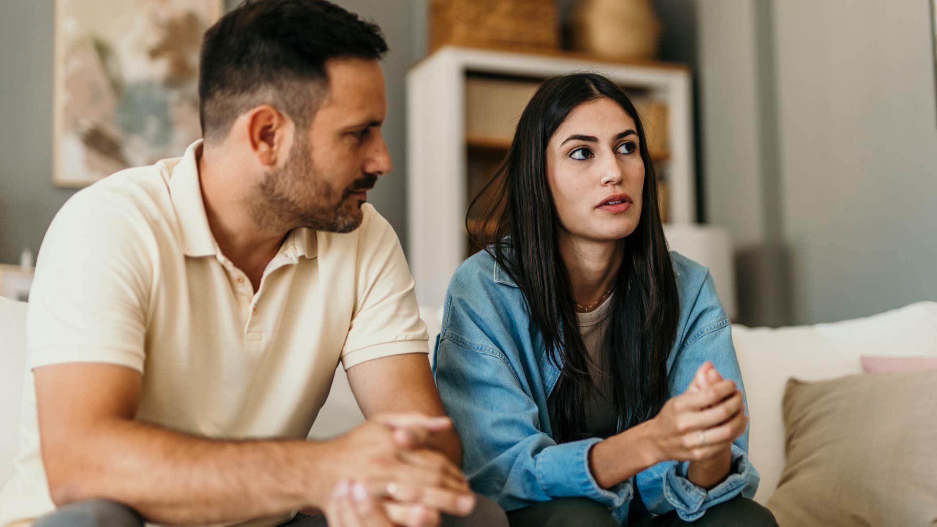 Man staring at his distracted wife on the couch