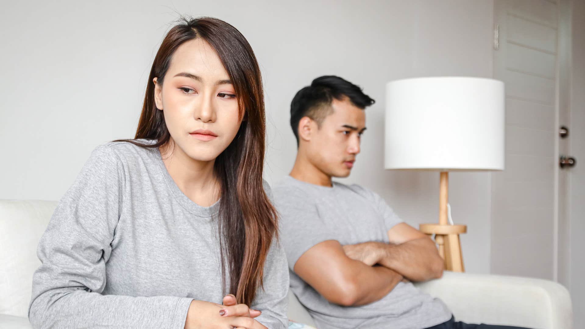 couple sitting on couch annoyed with each other