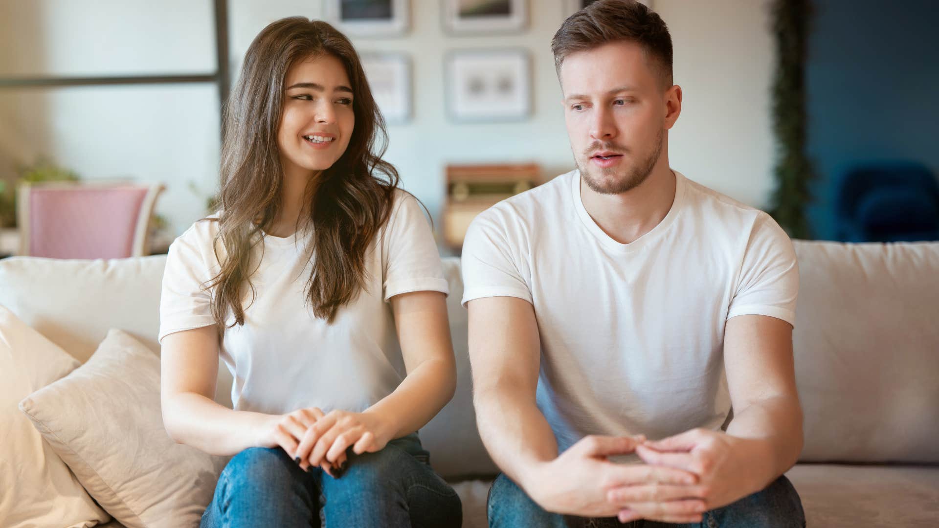 man and woman sitting on couch looking at each other awkwardly