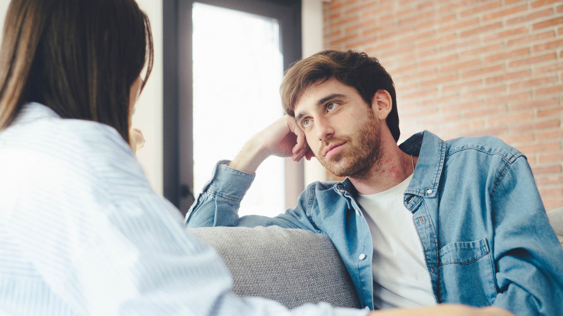 man and woman sitting on couch talking to each other