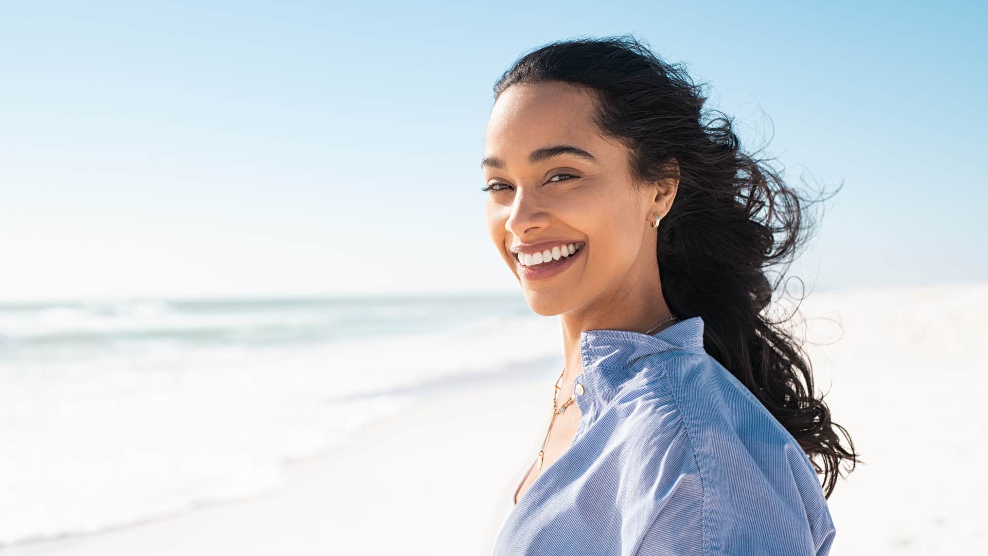 woman standing on beach surrounded by beautiful weather