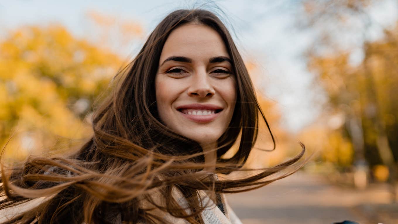 candid attractive young smiling woman walking in autumn park with coffee wearing checkered coat