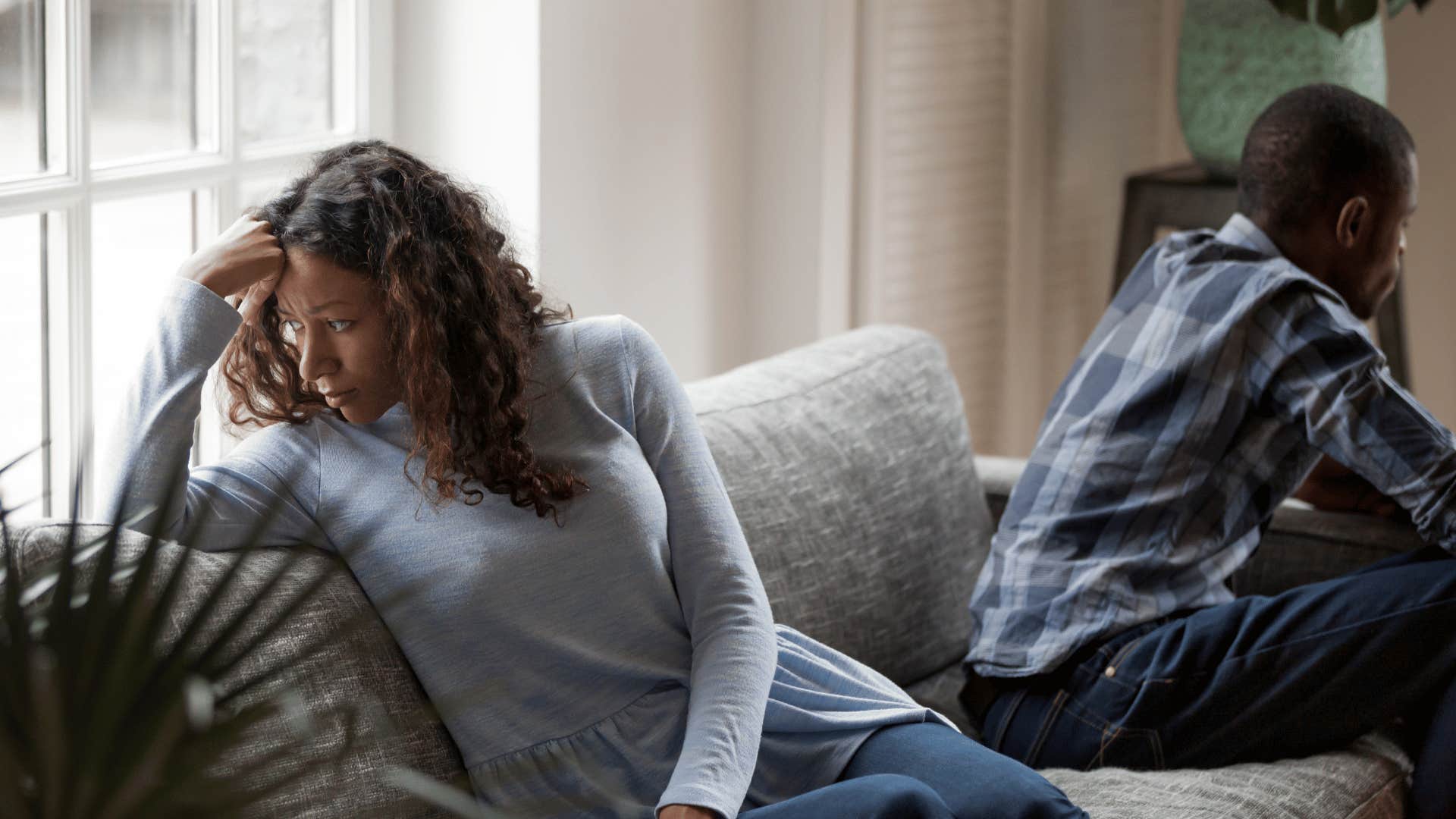 upset woman on couch with man faced away