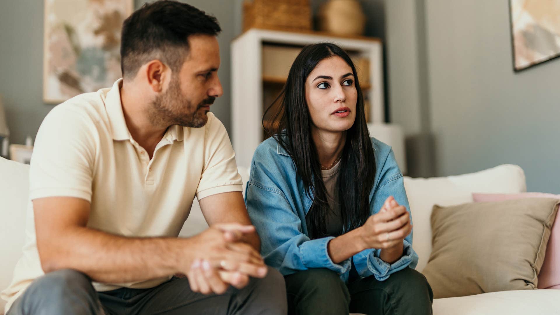 Woman looking annoyed sitting next to her partner on the couch.