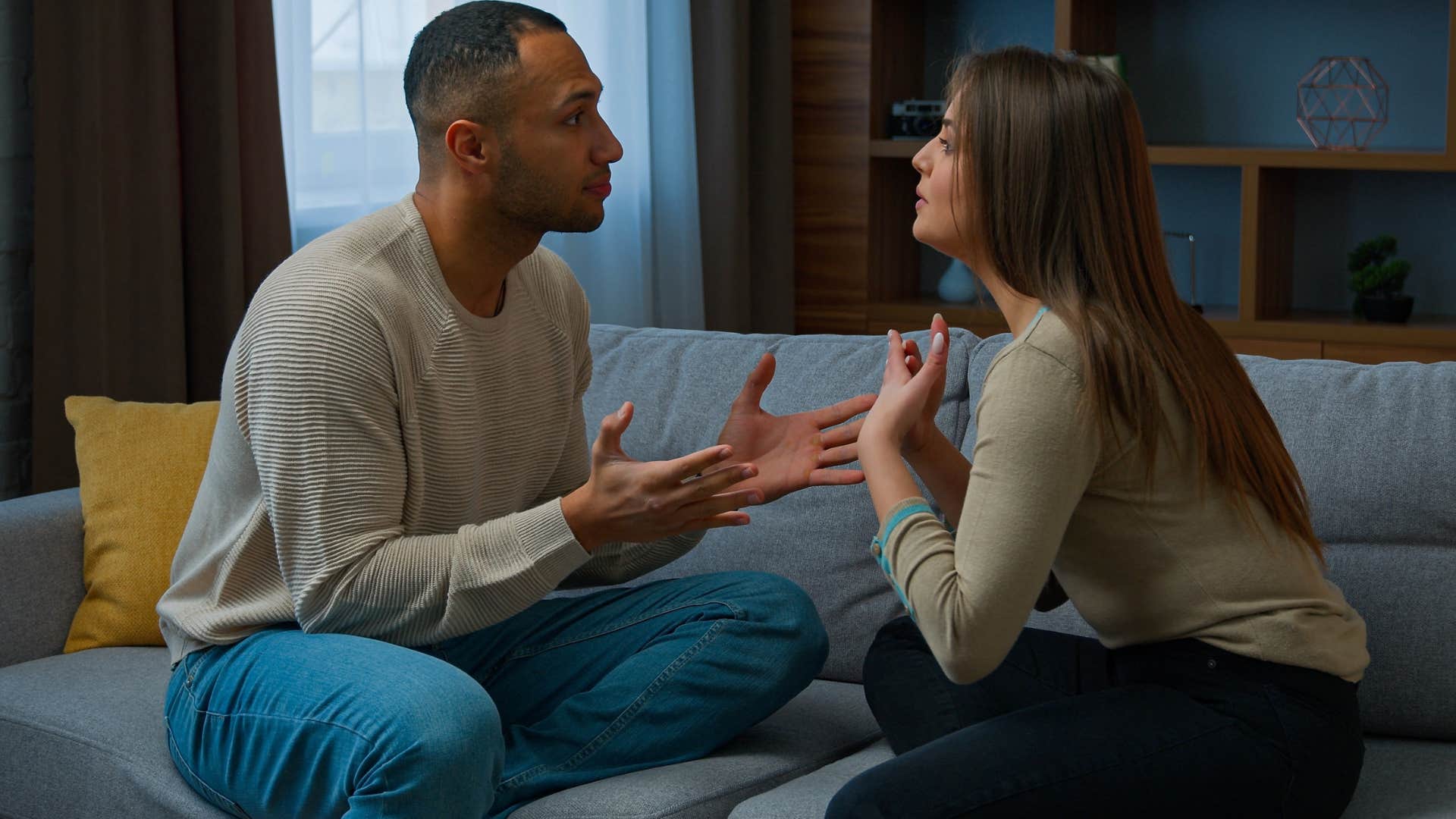 Couple arguing together on a couch.