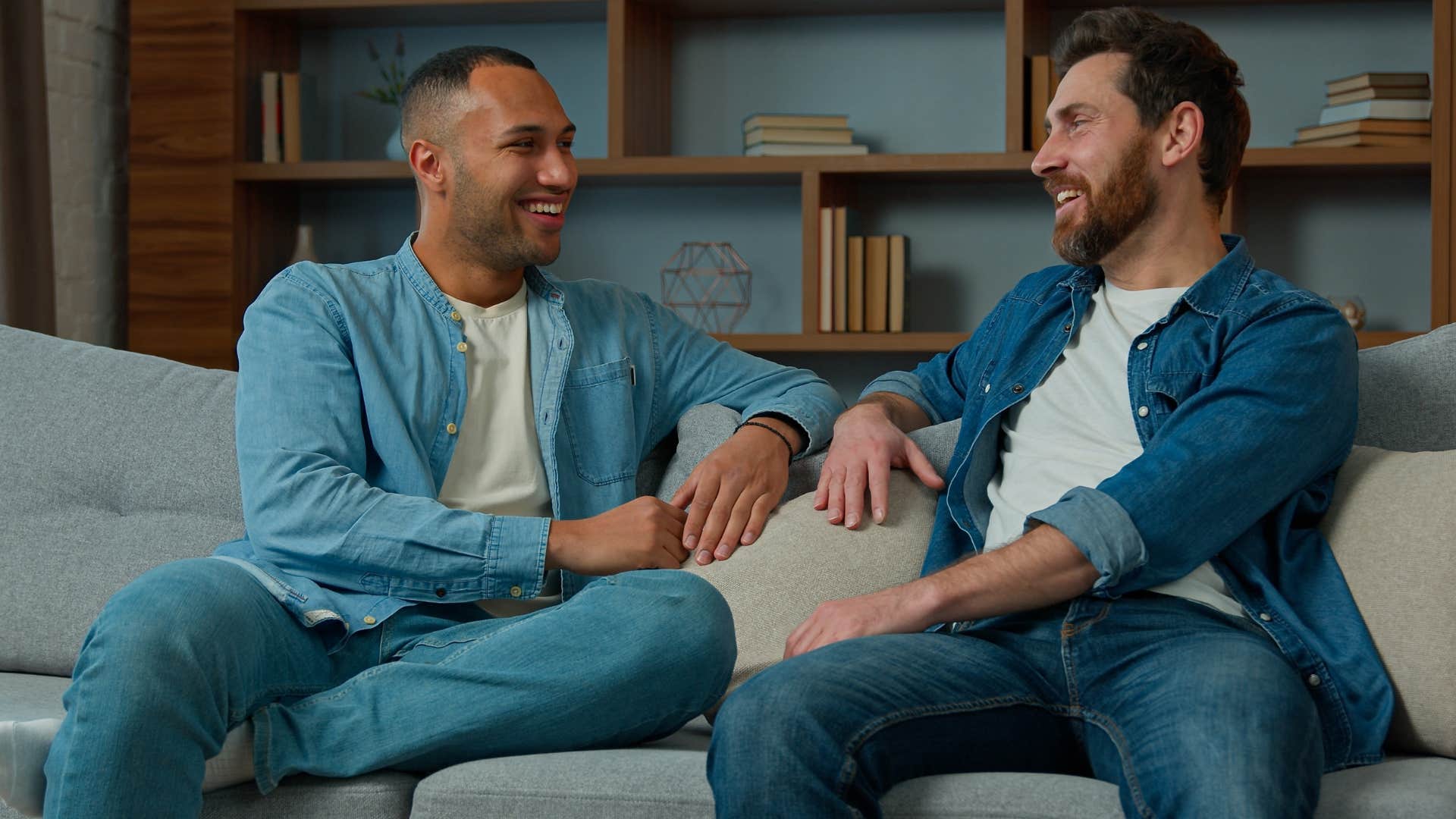 Two men smiling and talking on a couch