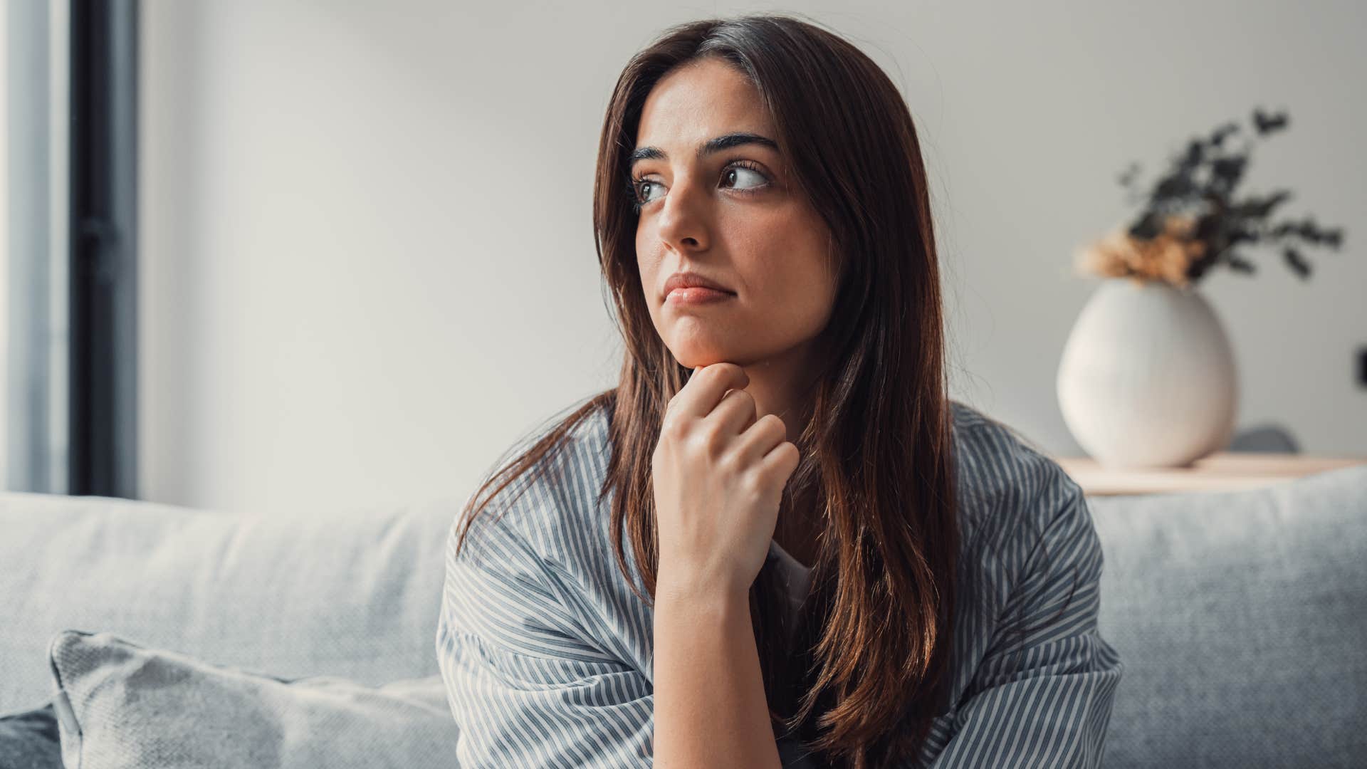 woman contemplating while sitting alone on couch