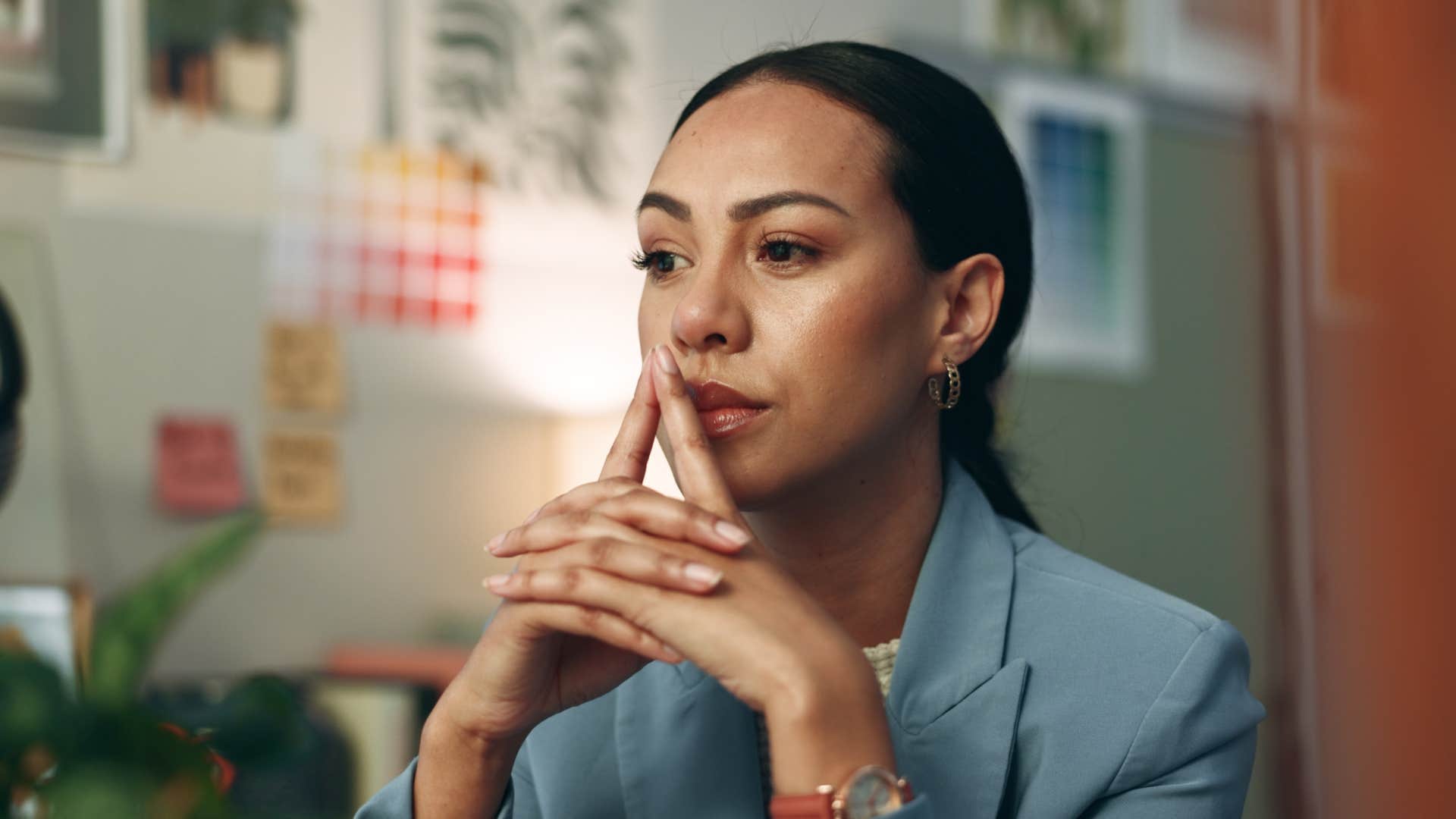 woman thinking with hands over mouth