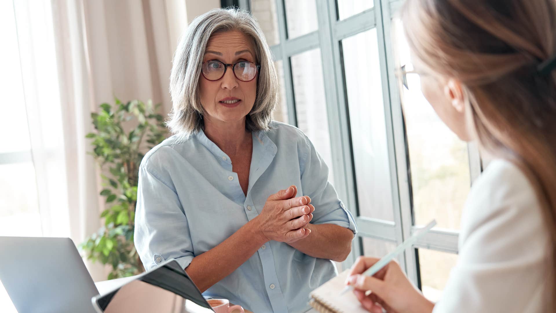 Older woman looking annoyed talking to a co-worker.