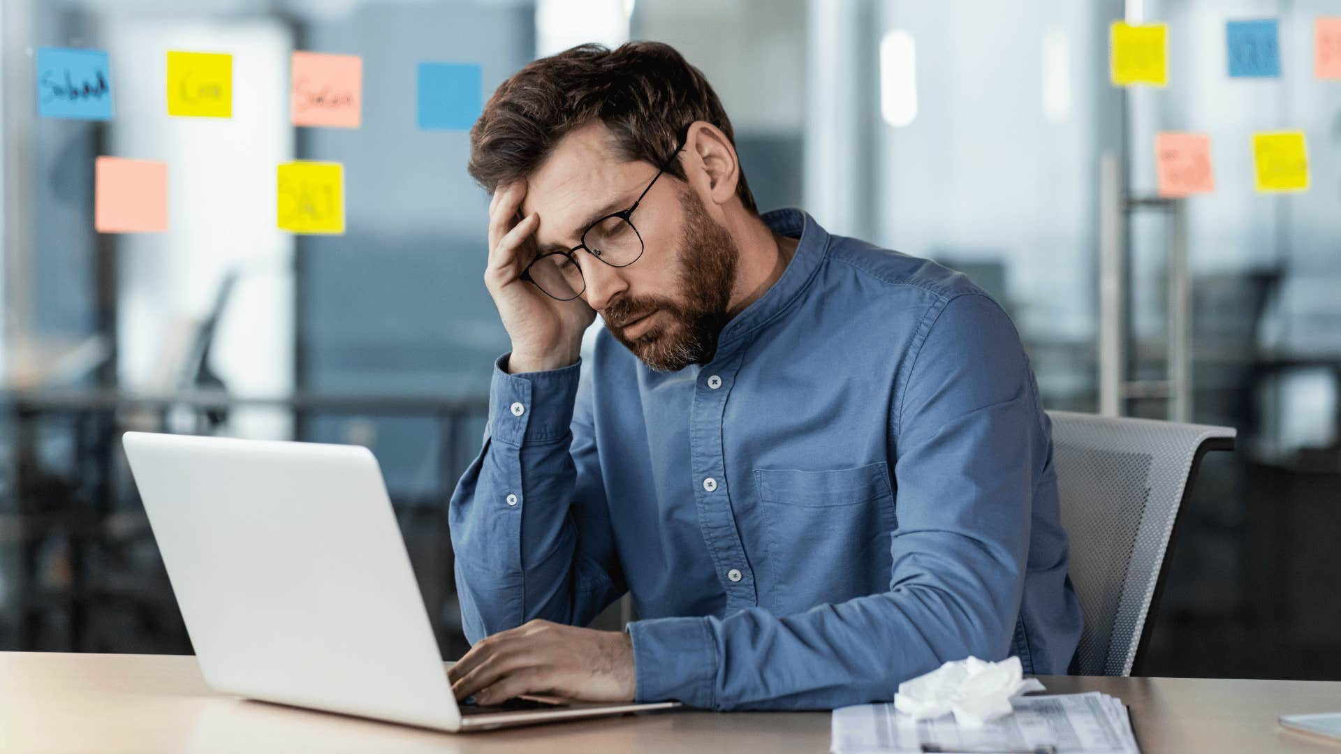 Man looking stressed while staring at laptop 