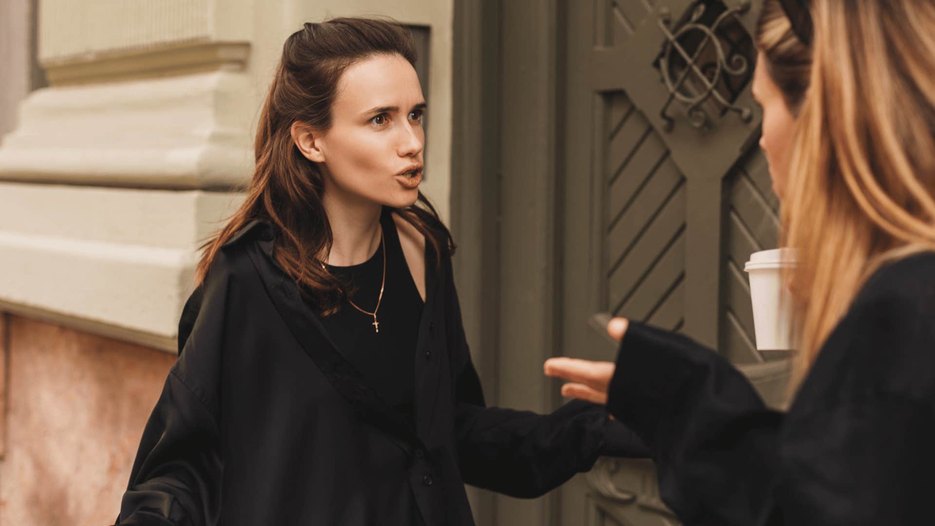 two women arguing outside of building