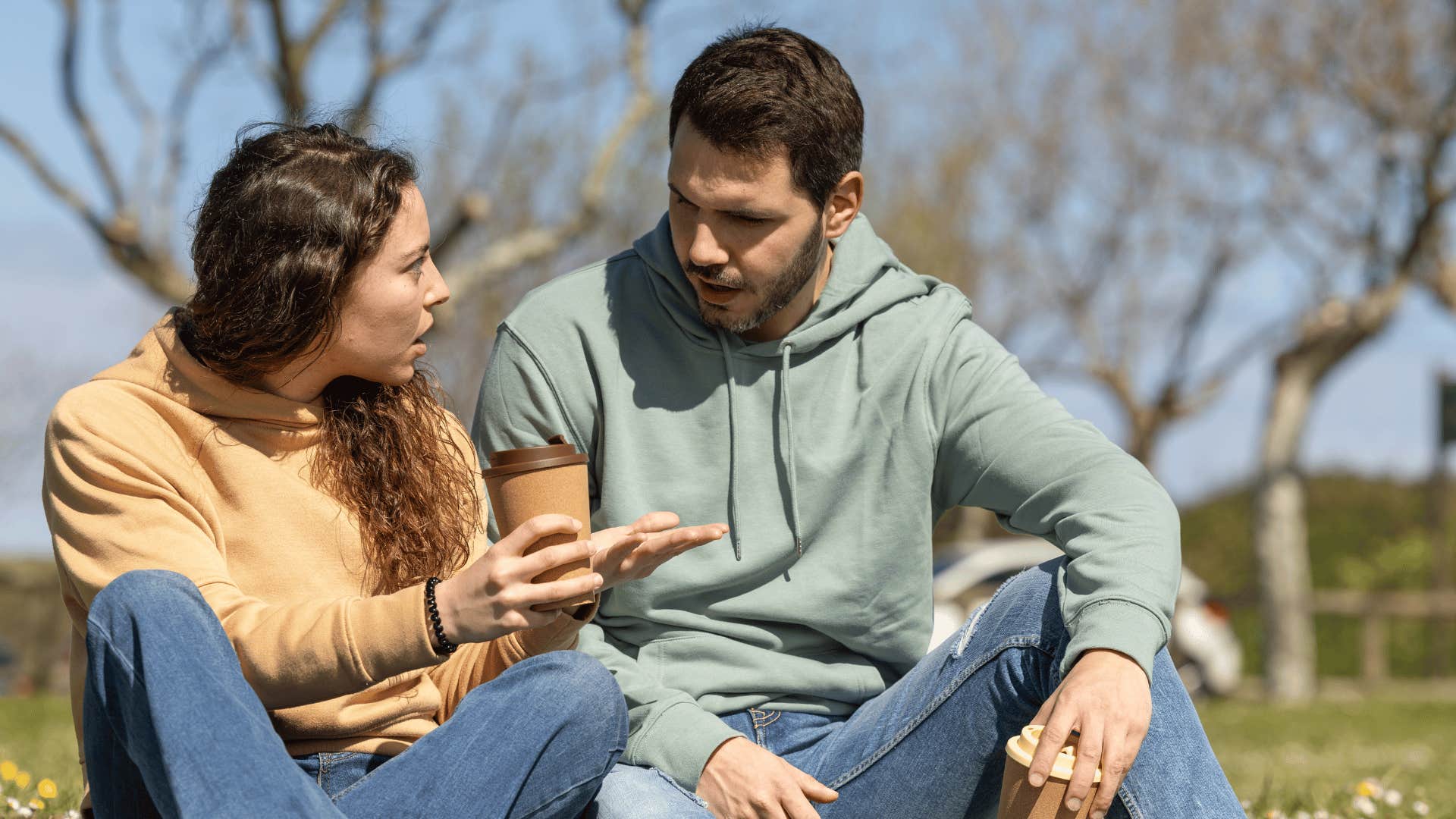 couple arguing outside while sitting on grass