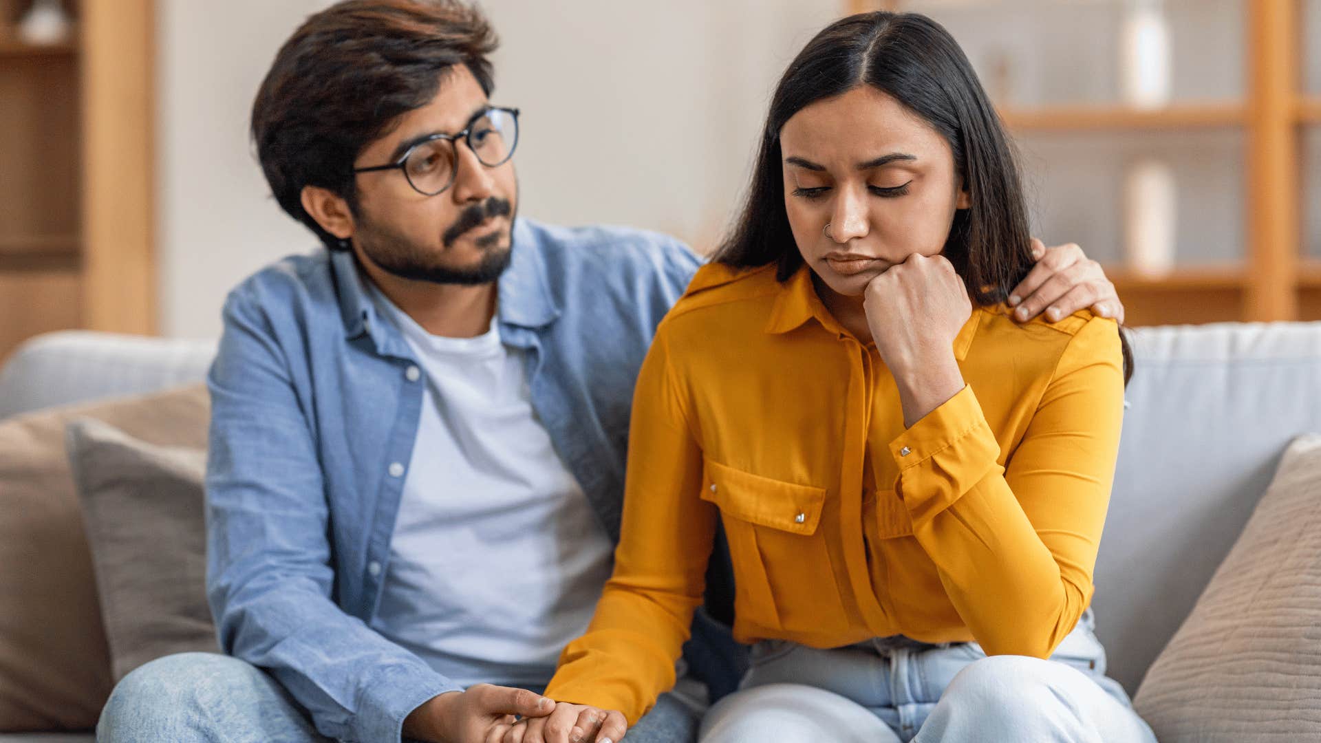 man comforting woman on couch