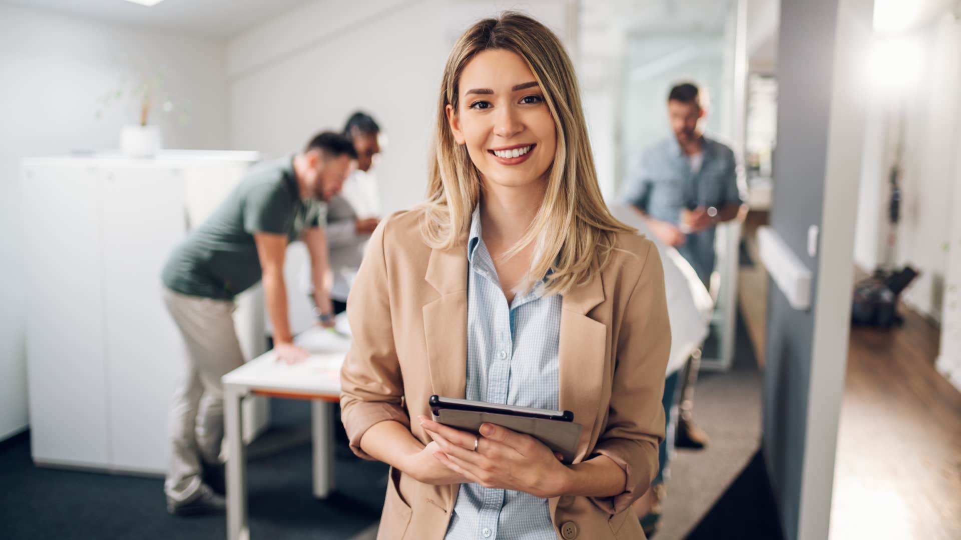 Smiling confident business leader looking at camera and standing in an office at team meeting