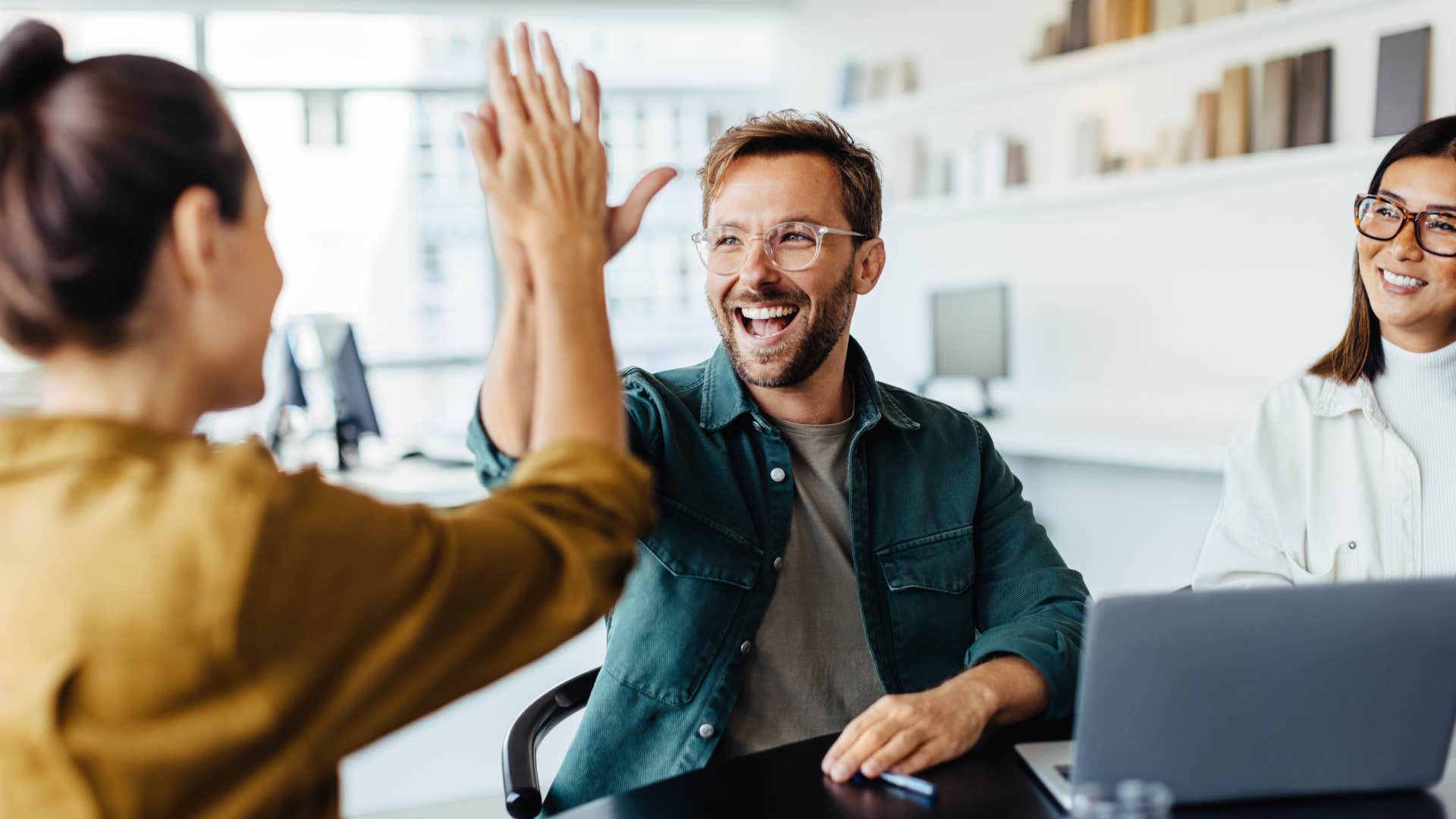 Successful business people giving each other a high five in a meeting