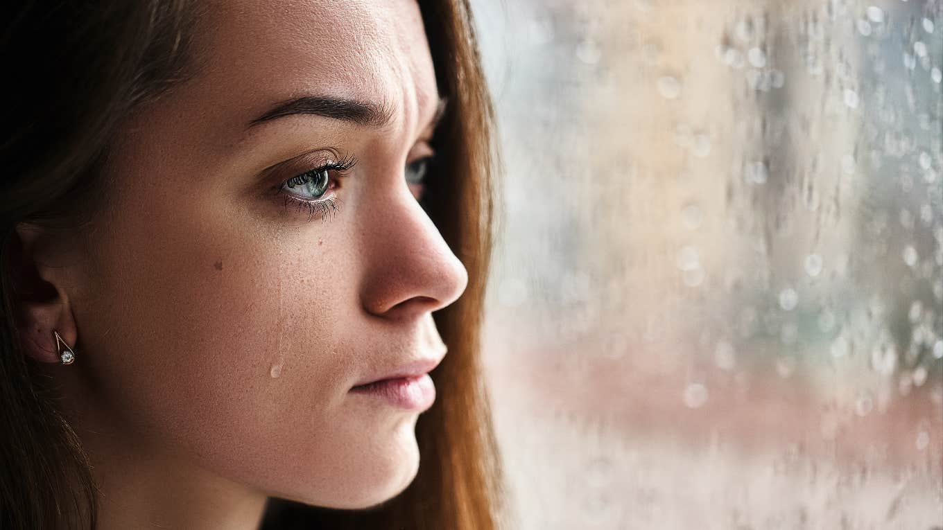 emotional upset woman crying while looking out the window