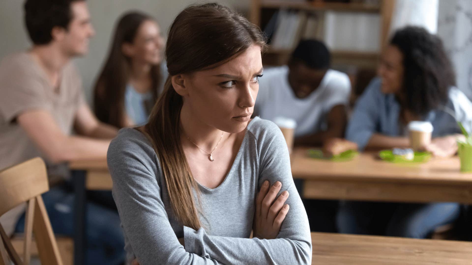 woman crossing arms looking upset while sitting alone